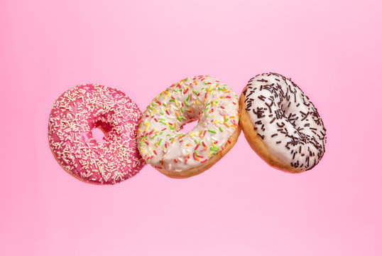 Flying sweet donuts isolated on pink background.
