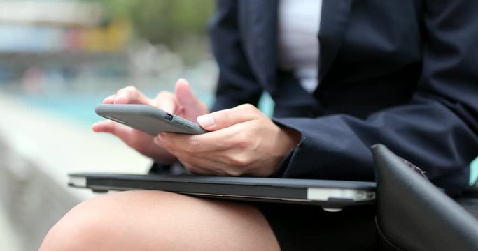 Business woman use of mobile phone and notebook computer at outdoor