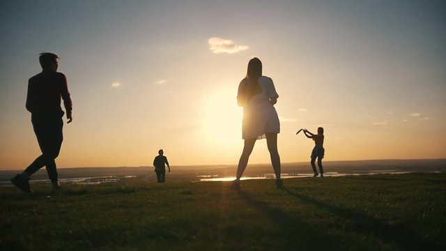 Happy young friends playing frisbee and having fun at sunset outdoors