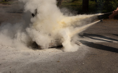 instructor showing how to use a  fire extinguisher on a training fire.