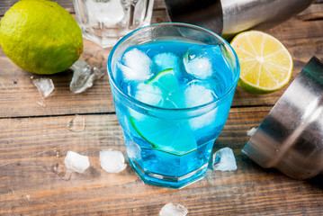 Colorful summer beverage, iced blue lagoon alcohol cocktail drink with lime and mint, bark...