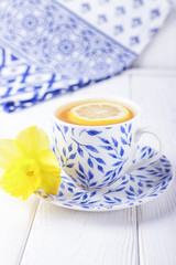 Lemon tea and yellow daffodil on a white background. Free space