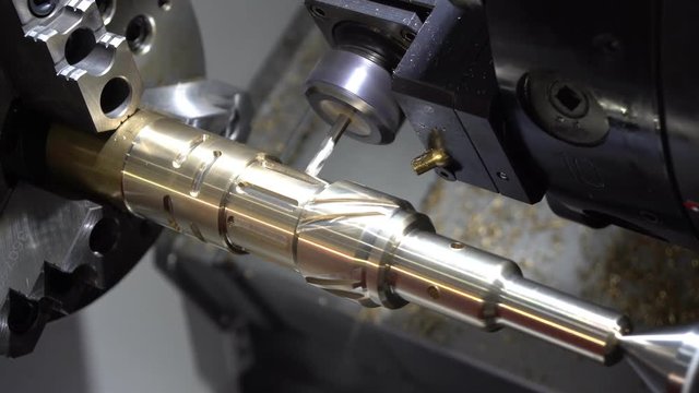 The CNC turning or lathe machine cutting groove slot at the brass shaft by the milling spindle. High technology manufacturing process.