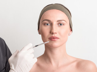 Expert beautician injecting botox in female face.