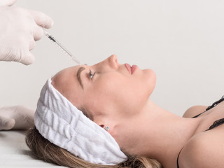 Expert beautician injecting botox in female face.