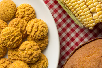 Delicious yellow cookie of corn. Sweet food of Festa Junina, a typical brazilian party. Snack on plate, red plaid table.