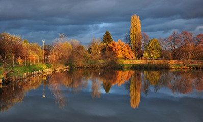 Autumn afternoon before a storm at the pond with colorful leaves on the trees around.............................................................................