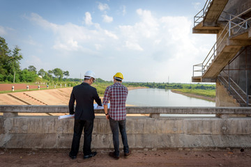 Business men meeting with Engineers and supervisors are standing reading the blueprints at the construction site.