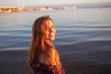 Young woman at sea, good mood and harmony. Beautiful red-haired girl. Cute cheerful young woman portrait at sunset