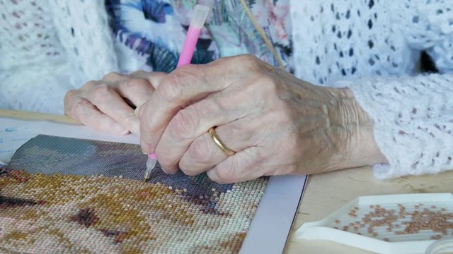 Diamond painting by elderly woman