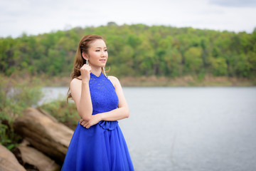 Beautiful woman wear blue evening dress over mountains and rivers background.