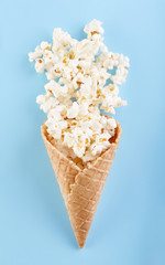 Popcorn in a waffle cone for ice cream on a bright blue background. Film. Fast food. Corn