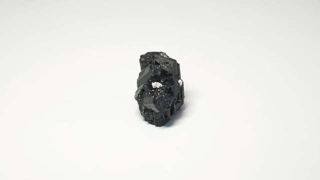 Macro shot of tourmaline mineral isolated over white background and spinning around
