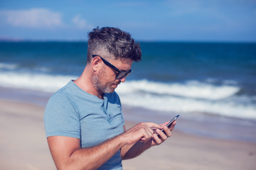 Young man using smartphone on the beach