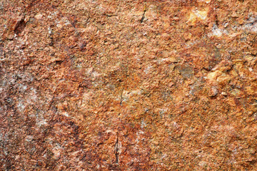 Pattern of surface of a red stone. Texture of stone in a natural environment. A granite stone