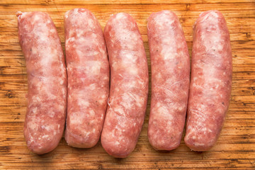 Sausages for frying on a wooden cutting board, top view