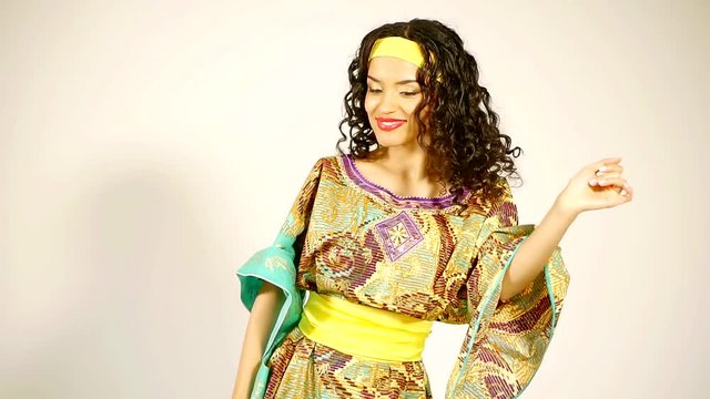 a young woman energetically and harmoniously dancing in an African outfit, the lady looks cute and funny