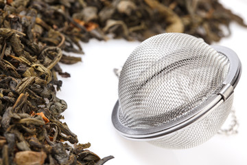 Tea strainer on a chain, with a mixture of dry green large-leaf tea with soursop, isolated on a white background.