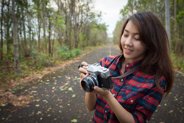 Young woman looking at old camera in her hands.