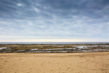 Sea shore with sand, pebbles and waves.