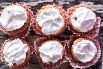 Cupcakes with white cream on a wooden background