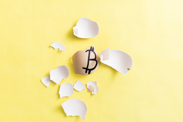 Egg with bitcoin painted on a yellow background. The concept of the collapse of the Crypto-currency