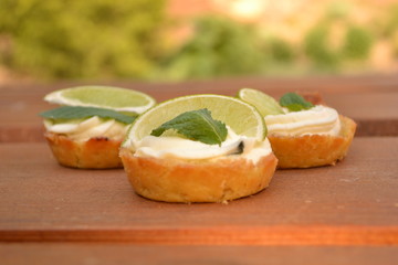Sweet creamy cakes with lime and mint on wooden table decoration