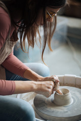 Handcrafted on a potter's wheel,Hands make clay from various items for home and sale in the store and at the exhibition, ceramic items are made in hand, beautiful girl makes products from clay