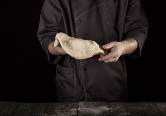 Layer of soft elastic dough in Baker's hands isolated on black