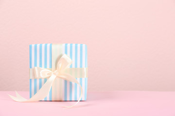 Beautiful gift box on table against color background