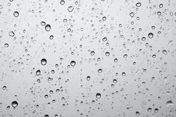 texture of rain drops on window glass over blur and cloudy sky background 