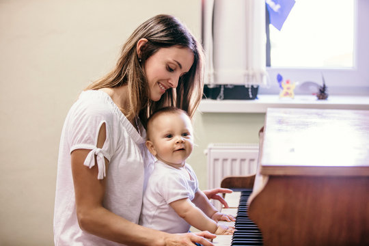 Mother and toddler baby boy, playing piano at home