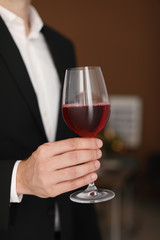 Young man with glass of wine indoors