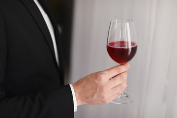 Young man with glass of wine indoors