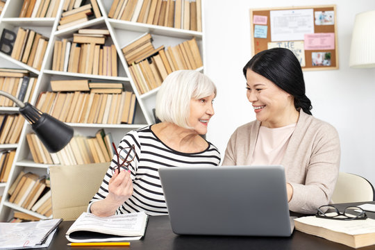 Technology in education. Cheerful tutor and mature student talking and staring at each other