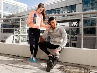 A girl and a young man rest after a workout in the city. Sports in the city. Friends smile after training.