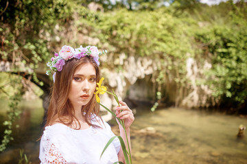 Fototapeta premium Young pretty woman in a white dress walking and posing in a forest near the river