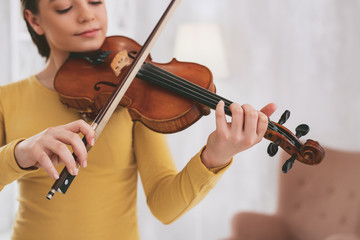 Relaxed atmosphere. Concentrated young female looking at strings while playing the violin
