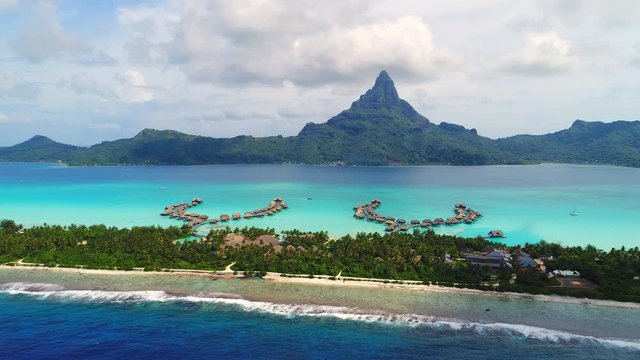 Aerial view of tropical paradise of Bora Bora, turquoise crystal clear water of scenic lagoon, typical overwater bungalows - South Pacific Ocean, French Polynesia, 4k UHD