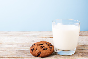 chocolate chip cookies and a glass of milk on a light table, on a blue background