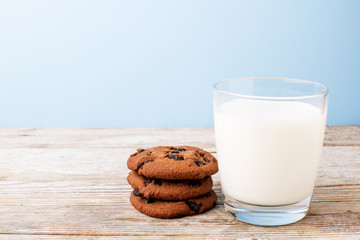 chocolate chip cookies and a glass of milk on a light table, on a blue background