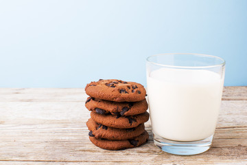 chocolate chip cookies and a glass of milk on a light table, on a blue background