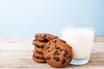 chocolate chip cookies and a glass of milk on a light table, on a blue background