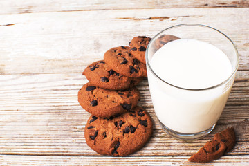 chocolate chip cookies and a glass of milk on an old board, top view
