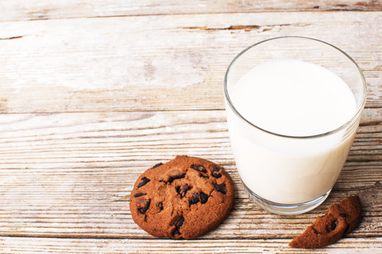 chocolate chip cookies and a glass of milk on an old board, top view