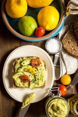 Fresh Avocado Spread Guacamole and Slices with Cherry Tomato and Black Sesame on a Piece of Bread. Healthy Breakfast Concept.