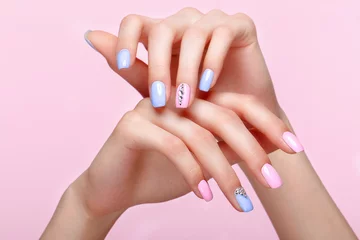 Poster Beautiful pink and blue manicure with crystals on female hand. Close-up. Picture taken in the studio © Kobrinphoto