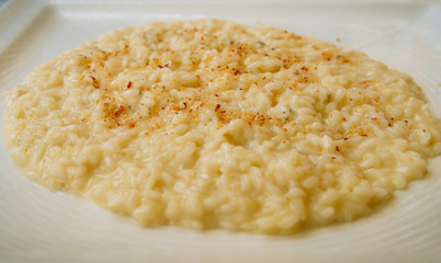 Flat-lay of delicious creamy risotto bowl with parmesan cheese on white plate