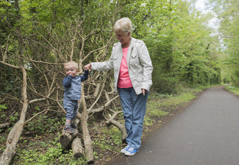 Grandmother and two year old grandson playing outdoors in a green park 