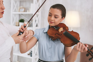 Relax your wrist. Attractive young female holding violin while going to play favorite melody